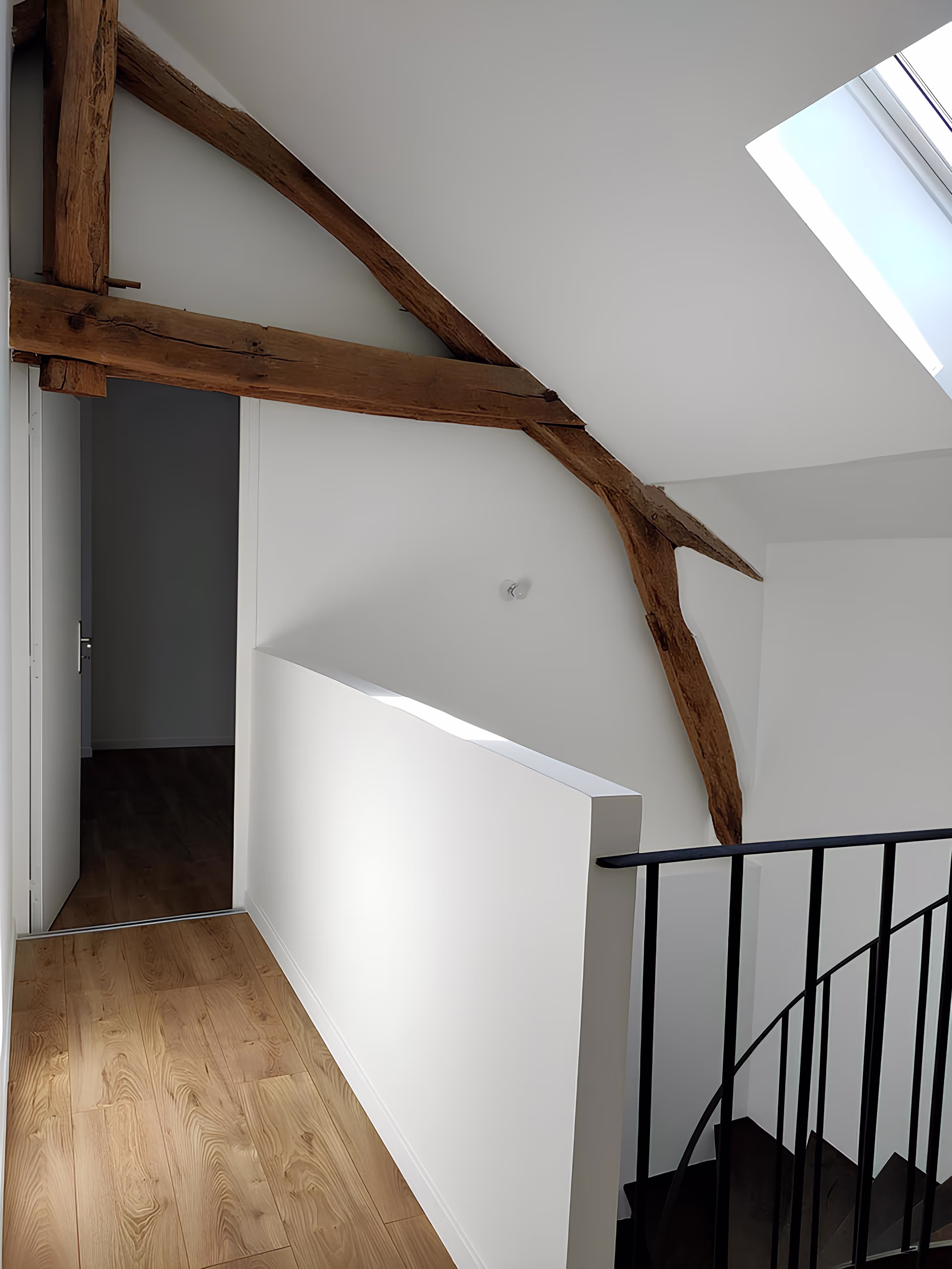 Palier lumineux rénové avec poutres apparentes et puits de lumière, Appartement Villeneuve par SINA Architecture.