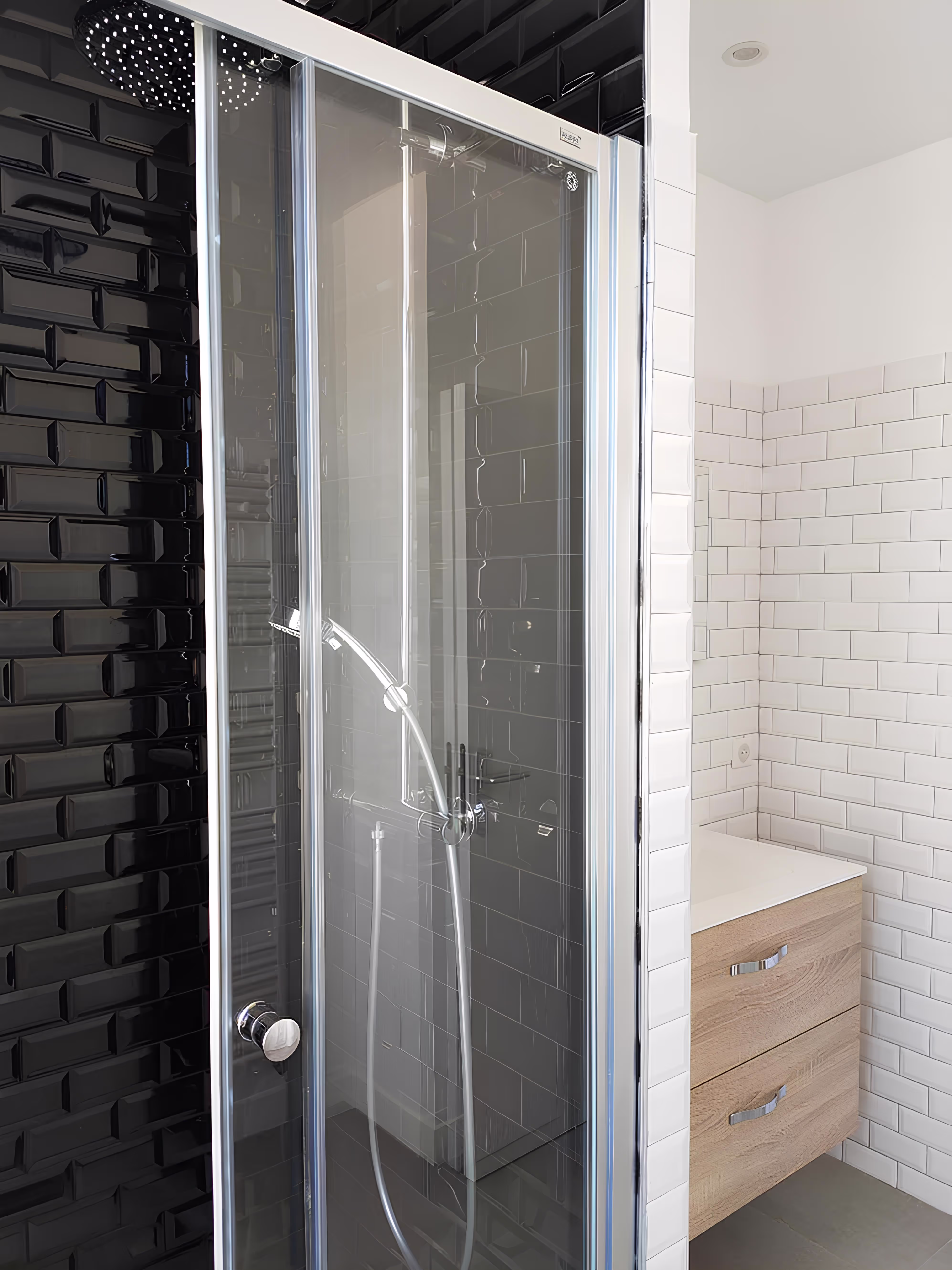 Salle de bain moderne rénovée avec douche vitrée, carrelage blanc et noir, Appartement Villeneuve à Villeneuve-sur-Auvers, SINA Architecture.