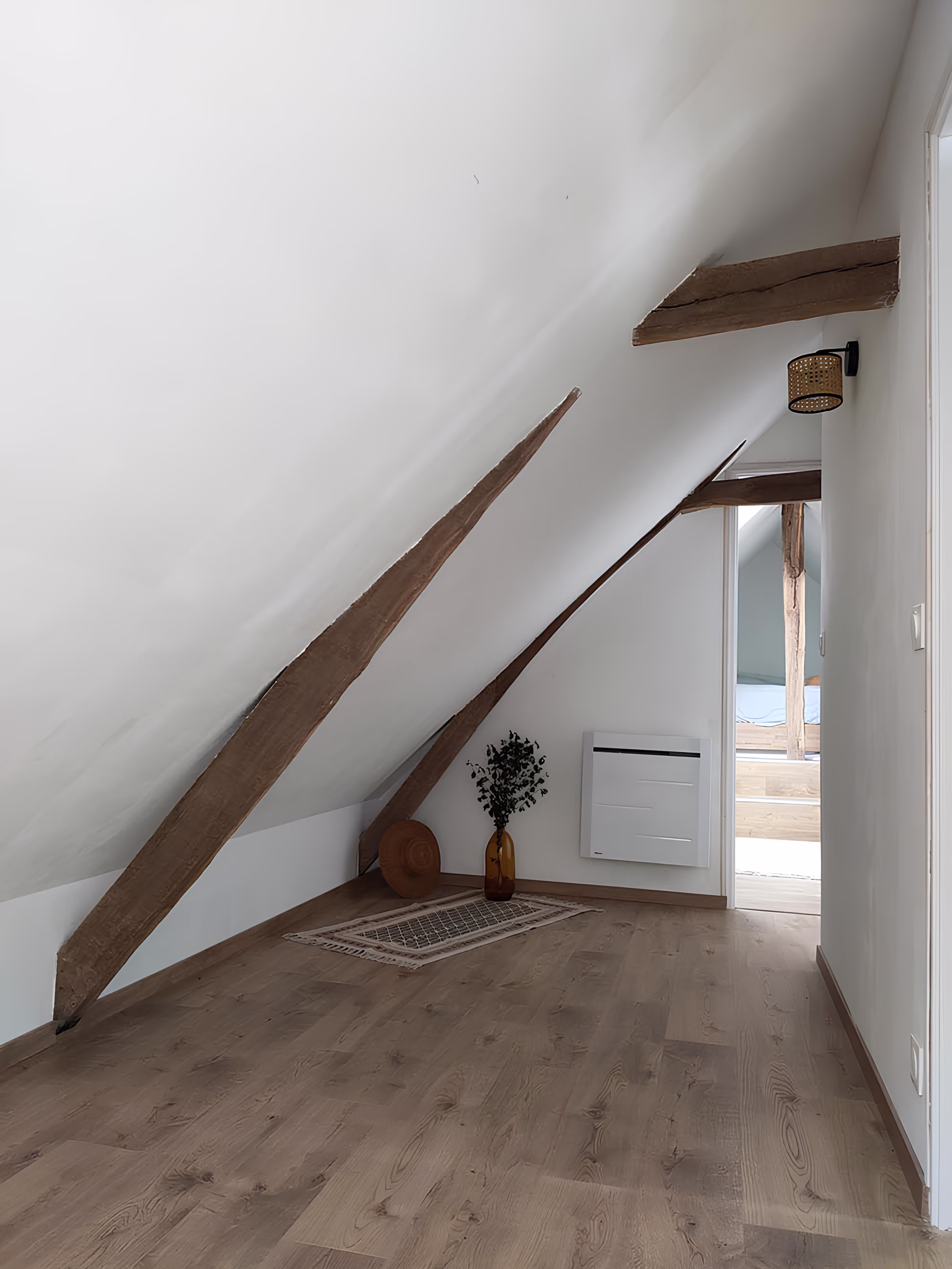 Espace sous combles aménagé avec poutres apparentes, parquet en bois clair, projet Longère Larronville par SINA Architecture