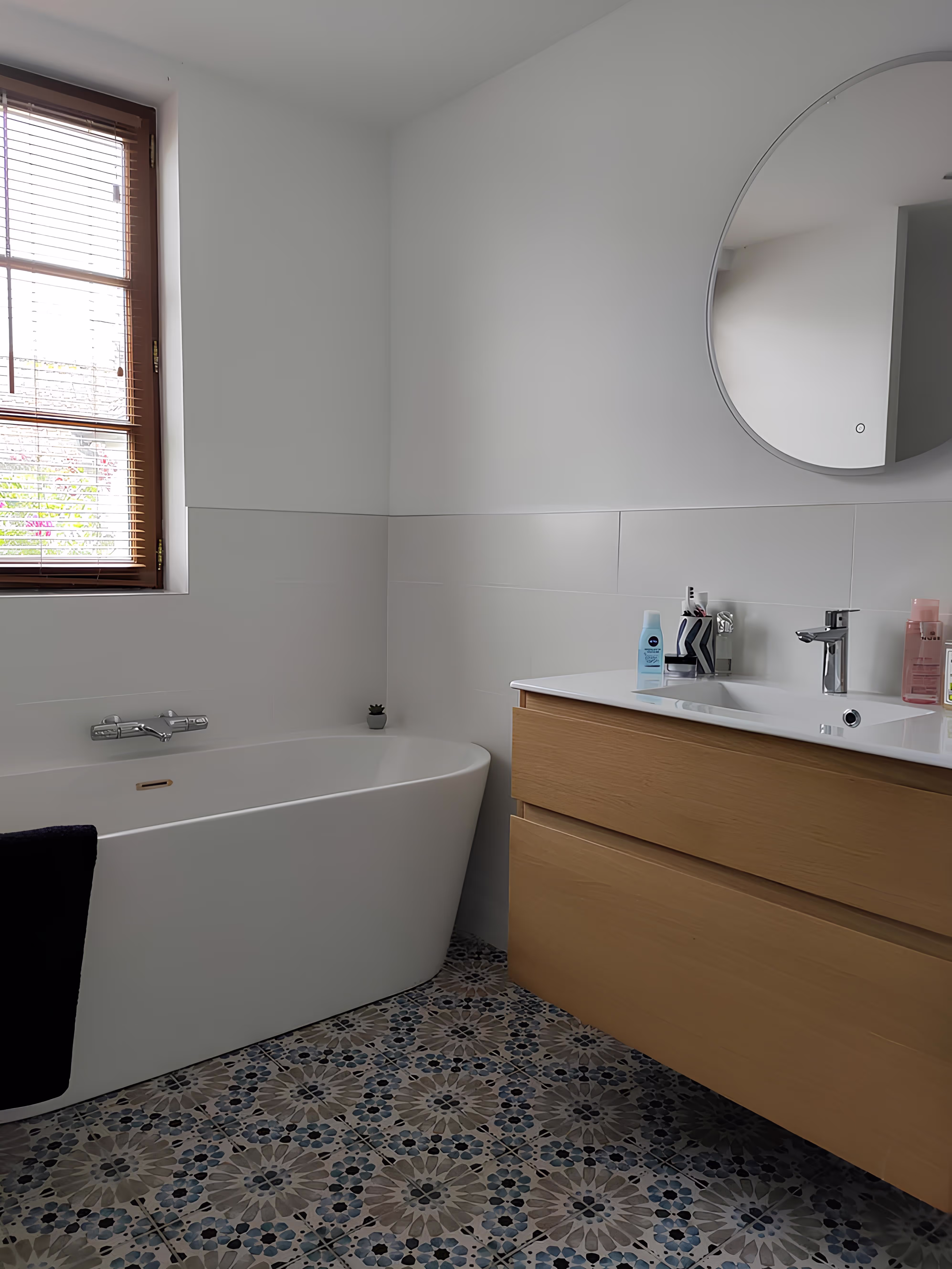 Salle de bain moderne rénovée dans la Longère Larronville par SINA Architecture, baignoire contemporaine, meuble bois et carreaux ciment.
