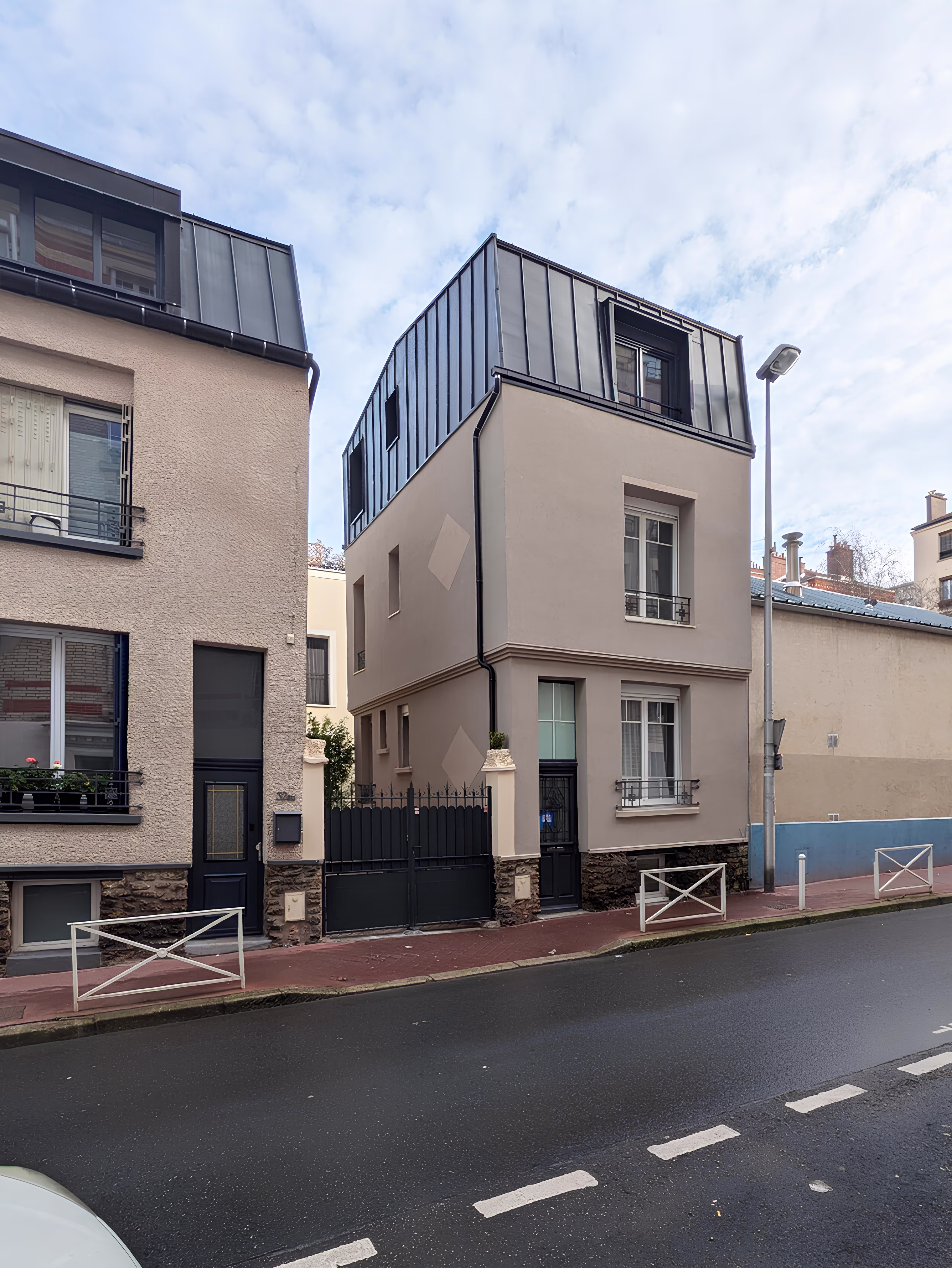 Vue de face de la façade principale rénovée avec toiture mansardée en zinc, projet Surélévation Boileau par SINA Architecture.