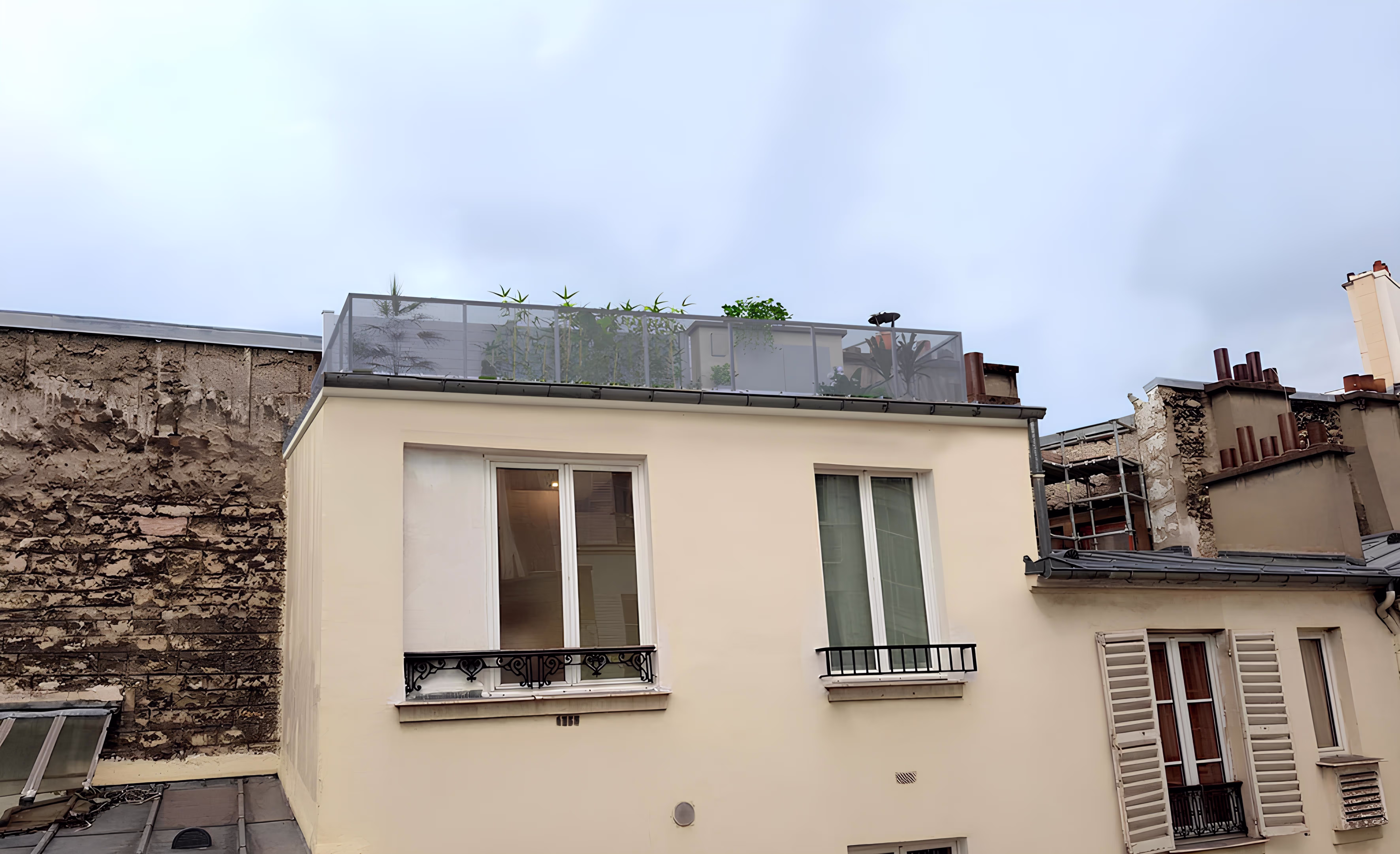 Vue de façade après projet, montrant l’intégration subtile du garde-corps et de la végétation sur la toiture, projet Terrasse FDC par SINA Architecture.